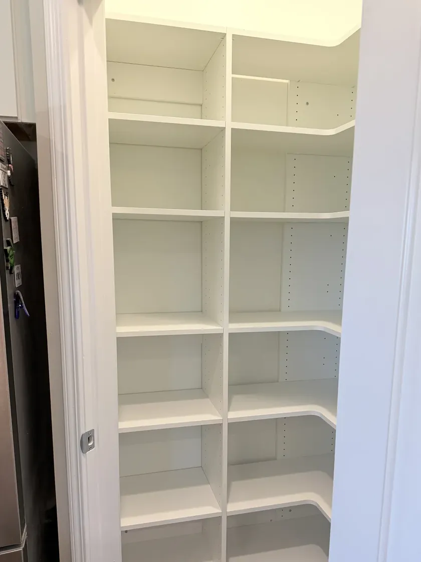 After: the same pantry with custom white shelving, deep drawers and pull-outs